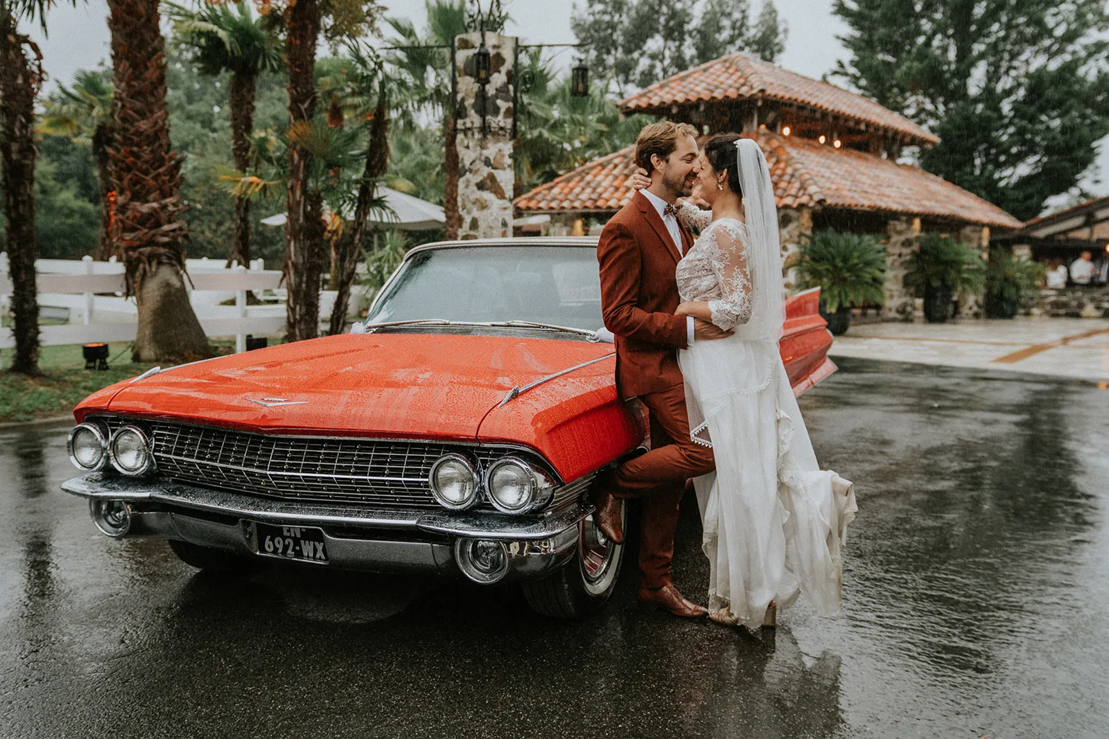 Les mariés enlacés devant une Cadillac rouge, devant le kiosque du Domaine