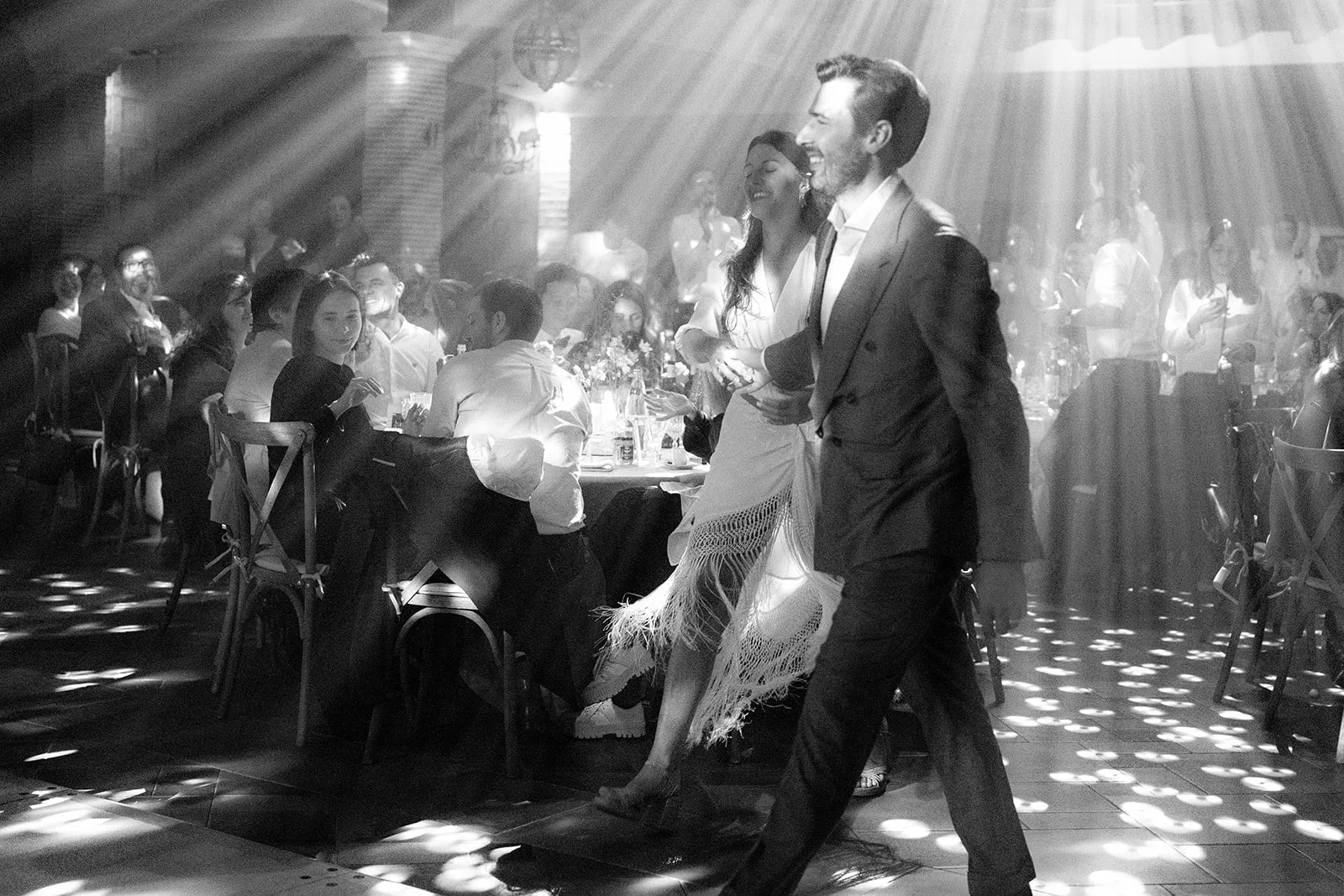 Les mariés ouvrent le bal entre les tables du dîner, photographie en noir et blanc