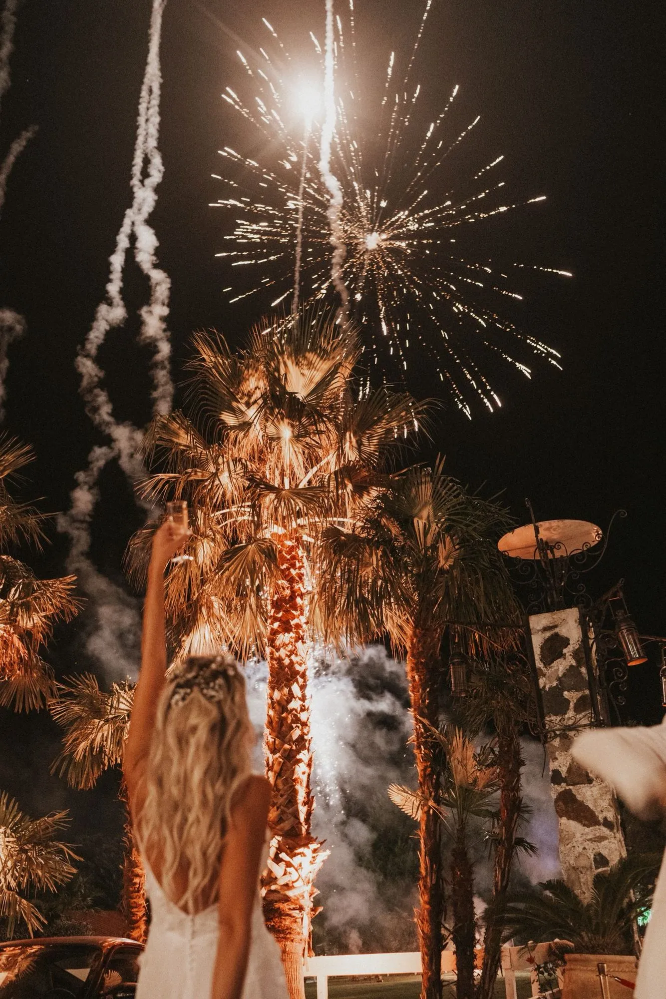 Feu d'artifice au-dessus des palmiers, la mariée de dos