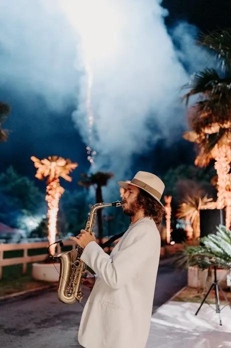 Saxophoniste devant les fontaines d'étincelles, à la nuit tombée