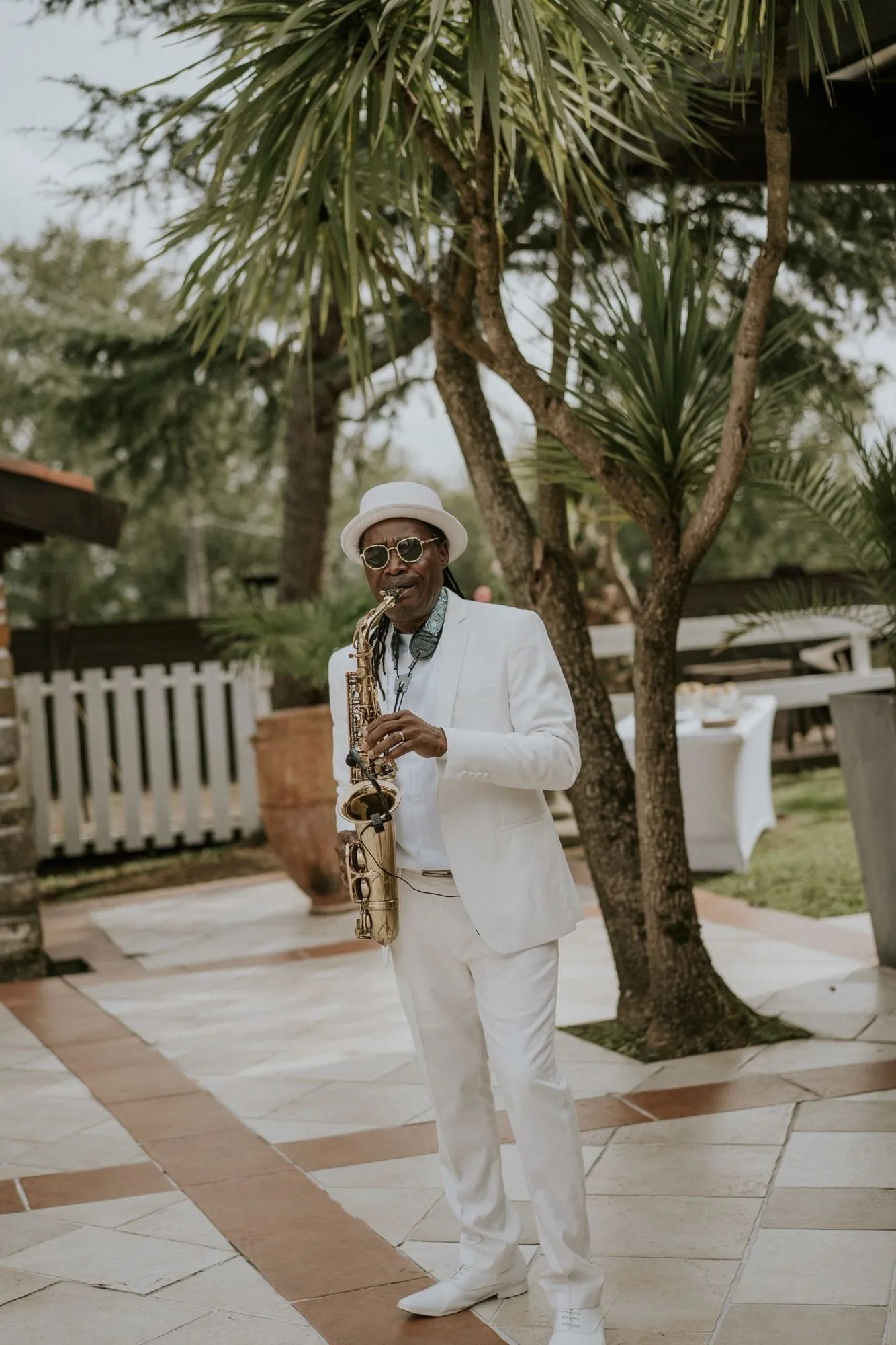 Saxophoniste en costume blanc jouant dans le jardin pendant le cocktail